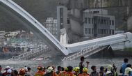 Rescue personnel look on at a bridge after it collapsed in the Nanfangao fish harbour in Suao township on October 1, 2019. The bridge collapsed in northeastern Taiwan on October 1 injuring at least 14 people as it smashed down onto fishing vessels moored 