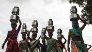 Women carry pitchers filled with water from an opening made to filter water next to a polluted lake in Thane, India June 13, 2019. Reuters/Prashant Waydande