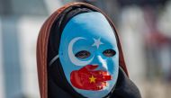A demonstrator wears a mask painted with the colours of the flag of East Turkestan and a hand bearing the colours of the Chinese flag during a protest in front of the Chinese consulate in Istanbul on October 1, 2019. AFP / Yasin Akgul
 