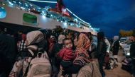 Refugees and migrants wait to be transferred to a camp in northern Greece, after their arrival from the island of Lesbos to the port of Piraeus near Athens early on October 7, 2019.   AFP / LOUISA GOULIAMAKI