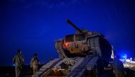 A Turkish army's tank drives down from a truck as Turkish armed forces drive towards the border with Syria near Akcakale in Sanliurfa province on October 8, 2019. AFP / BULENT KILIC