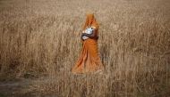 FILE PHOTO: A woman carries her baby as she walks through a wheat field in Amroha district in Uttar Pradesh, April 17, 2014. Reuters/Adnan Abidi