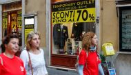 People walk in front of a shop in downtown Rome as Italy's cabinet prepares to approve a 2020 budget draft before sending the document to Brussels for scrutiny by the European Commission, Rome, Italy, October 15 2019. REUTERS/Remo Casilli
