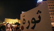 A Lebanese protester lifts a placard that reads 