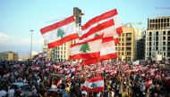 Demonstrators carry national flags during an anti-government protest in downtown Beirut, Lebanon October 20, 2019. REUTERS/Ali Hashisho