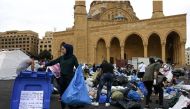 A young woman sorts recycling into a bin in front of the Mohammad al-Amin mosque in Beirut, Lebanon on 23 October 2019. Thomson Reuters Foundation/Finbar Anderson