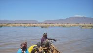 Armed fishermen return from a fishing expedition aboard a boat on March 24, 2017 near Lowarengak, on the western shores of Lake Turkana, northern Kenya. AFP / Tony Karumba
