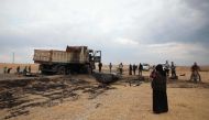 Syrian locals near a destroyed truck at the spot where Abu Hassan al-Muhajir, the Islamic State (IS) group's spokesman was reportedly killed in a raid in the northern Syrian village of Ayn al-Bayda near Jarablus. AFP / Aaref WATAD