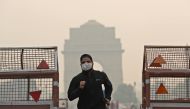 A man wearing a mask runs past the India Gate on a smoggy morning in New Delhi, India, October 28, 2019 REUTERS
