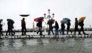 People walk on a catwalk in the flooded St.Mark's Square during a period of seasonal high water in Venice, Italy November 12, 2019. Reuters/Manuel Silvestri
 
