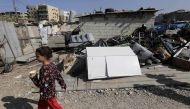 A Lebanese child walks past scrap metal for recycling at an impoverished neighbourhood in al-Mani area of the port city of Tripoli, north of Beirut, on November 7, 2019. AFP / JOSEPH EID