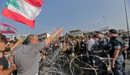 Lebanese demonstrators try to remove the barbed-wire and metal rail, placed by anti-riot police, on the road leading to the Presidential Palace in Baabda, on the eastern outskirts of Beirut on November 13, 2019, nearly a month into an unprecedented anti-g