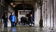 People walk across a floodedarcade by St. Mark's Square on November 14, 2019 in Venice. (AFP / Filippo MONTEFORTE)