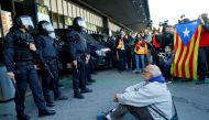A man sits on the ground in front of riot police officers as Catalan separatist protesters attend a demonstration outside the Sants train station in Barcelona, Spain November 16, 2019. REUTERS/Enrique Calvo