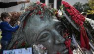 A woman places a red carnations on the monument in memory of the victims of the 1973 student's uprising against the US-backed military junta at the Athens' polytechnic school on November 16, 2019.  AFP / Louisa Gouliamaki 