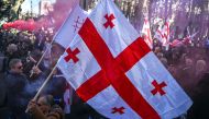Georgian opposition supporters carry Georgian flags amid coloured smoke as they protest outside the parliament in central Tbilisi on November 17, 2019, to demand the government's resignation and early parliamentary polls.. / AFP / Vano Shlamov 
