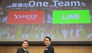 Kentaro Kawabe (L), CEO and president of Z Holdings and Takeshi Idezawa (R), CEO and president of LINE shake hands during a joint press conference in Tokyo on November 18, 2019. Japan's Z Holdings, formerly Yahoo Japan, will merge with mobile chat app ope