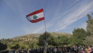 Lebanese protesters raise a national flag as they take part in a 20km (12 miles) march in the Bisri Valley, southwest of the capital Beirut on November 22, 2019, to protest against the construction of a dam in the area. AFP / JOSEPH EID