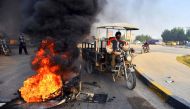 Iraqis walk past burning tyres at a roadblock in the central holy shrine city of Najaf on November 27, 2019, amid ongoing anti-government demonstrations.  AFP / Haidar HAMDANI