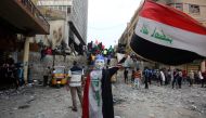 An Iraqi demonstrator wearing a Guy Fawkes mask in reverse and draped in a national flag waves another national flag before others celebrating the resignation of Prime Minister Adel Abdul-Mahdi's government, during a demonstration along Rasheed Street in 
