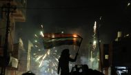 An Iraqi demonstrator waving the national flag is silhouetted during clashes with security forces in the holy shrine city of Karbala on November 29, 2019, amid ongoing anti-government protests.   AFP / Mohammed SAWAF
