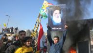 An Iraqi supporter lifts a picture of Iraq's top cleric Grand Ayatollah Ali Sistani during a rally in front of the US embassy in Baghdad, on December 31, 2019. (AFP / AHMAD AL-RUBAYE)
