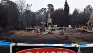 A woodchip mill burnt by bushfires is seen as smoke rises in Eden in Australia's New South Wales state on January 6, 2020. Reserve troops were deployed to fire-ravaged regions across three Australian states on January 6 after a torrid weekend that turned 