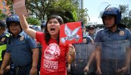 A protester shouts anti-US slogans next to Philippine policemen during a rally in front of the US embassy in Manila on January 6, 2020, demonstrating against the US strike that killed Iranian commander Qasem Soleimani in Iraq. A US drone strike killed top