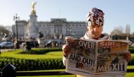 Royal super fan John Loughery holds a copy of a British newspaper as he poses for the media outside of Buckingham Palace in London on January 9, 2020. (AFP / Tolga AKMEN)
 
