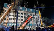 This photo taken on January 13, 2020 shows Chinese rescuers watching as a bus is lifted out after a road collapse in Xining in China's northwestern Qinghai province. An enormous sinkhole swallowed passers-by and a public bus in northwest China, reported s