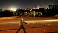 A civilian walks past members of the Sudanese Rapid Support Forces (RSF) are seen near the area where gunmen opened fire outside buildings used by Sudan's National Intelligence and Security Service (NISS) in Khartoum, Sudan January 14, 2020. REUTERS/Moham