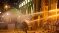 Lebanese protesters take cover as riot police spray them with water from behind a barricaded road leading to parliament in central Beirut  amid ongoing anti-government demonstrations. Lebanese anti-riot police fired rubber bullets and water cannons at sto