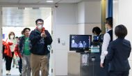 This picture taken on January 13, 2020 shows Taiwan's Center for Disease Control (CDC) personnel (R) using thermal scanners to screen passengers arriving on a flight from China's Wuhan province, where a SARS-like virus was discovered and has since spread,
