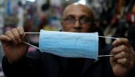 A Pakistani vendor holds a paper mask for sale at his shop, as pharmacies are running out of face masks due to the large demand from Asian people, who buy and send them to relatives in their countries of origin, amid the new coronavirus outbreak, in Barce