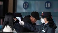 This photo taken on February 1, 2020 shows security personnel checking the temperature of a passenger wearing a face mask at Beijing Railway Station in Beijing. The number of infections in China's coronavirus outbreak has passed 14,300 nationwide with 2,5