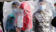 Passengers wearing masks and covered with plastic bags walk outside the Shanghai railway station in Shanghai, China, as the country is hit by an outbreak of a new coronavirus, February 9, 2020. REUTERS/Aly Song