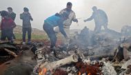 People search for scrapes of metal among the debris of a Syrian military helicopter that was shot down on February 14, 2020, in the western countryside of Aleppo province. (AFP / Omar HAJ KADOUR)