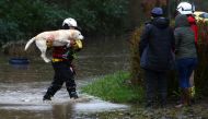 Members of the emergency services evacuate residents and their dogs from flooded houses by rescue boat after the River Taff burst its banks in Nantgarw, south of Ponypridd in south Wales on February 16, 2020, after Storm Dennis caused flooding across larg