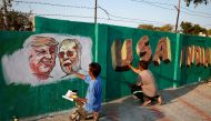 A man applies finishing touches to paintings of US President Donald Trump and India's Prime Minister Narendra Modi on a wall as part of beautification along a route that Trump and Modi will be taking during Trump's upcoming visit, in Ahmedabad, India, Feb