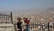 Afghan boys who sell boiled eggs climb to a hilltop overlooking Kabul, Afghanistan February 23, 2020. REUTERS/Mohammad Ismail
