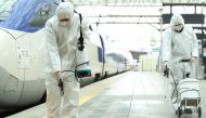 Railway workers wearing protective gear spray disinfectant as part of preventive measures against the spread of the COVID-19 coronavirus, at a railway station in Seoul on February 25, 2020. AFP / YONHAP 