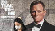 A woman wearing a facemask amid fears of the spread of the COVID-19 novel coronavirus walks past a poster for the new James Bond movie ‘No Time to Die’ in Bangkok on February 28, 2020. AFP / Mladen Antonov
 