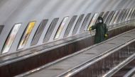 An employee wearing protective gear rides an escalator while spraying disinfectant to sanitize a metro station over coronavirus fears in Tbilisi, Georgia March 3, 2020. REUTERS/Irakli Gedenidze