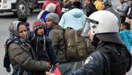 A woman and a child are blocked by policemen as police push back migrants back from Moria camp who gathered near the port of Mytilene on the island of Lesbos, hoping to get a ferry to Athens on March 4, 2020. AFP / Louisa Gouliamaki
 