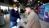 A Palestinian worker wearing a mask sanitizes the hands of a customer amid coronavirus precautions, in a supermarket in Gaza City March 8, 2020. Reuters/Mohammed Salem