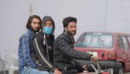 A boy wearing a facemask as a preventive measure against the spread of the COVID-19 coronavirus outbreak, rides on a motorbike along with others in Rawalpindi on March 4, 2020.  AFP / Farooq NAEEM 