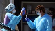 Medical workers at Kaiser Permanente French Campus test a patient for the novel coronavirus, COVID-19, at a drive-thru testing facility in San Francisco, California on March 12, 2020.  / AFP / Josh Edelson 