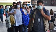 Passengers wear protective face masks to prevent the spread of the new Coronavirus, COVID-19, outside the Toncontin International Airport, in Tegucigalpa, on March 14, 2020. Honduran government has prohibited citizens from Europe, China, Iran, and South K