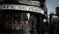 A man walks past the closed Cafe de Flore in Paris' Saint-Germain-des-Pres district on March 15, 2020, as cafes and restaurants are closed amid the COVID-19 outbreak, caused by the novel coronavirus.  AFP / Philippe Lopez 
