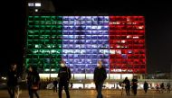  People walk at Rabin square as the municipality building is lit in the colours of the Italian flag in solidarity with the coronavirus situation, in Tel Aviv, Israel March 15, 2020 REUTERS/ Corinna Kern 
